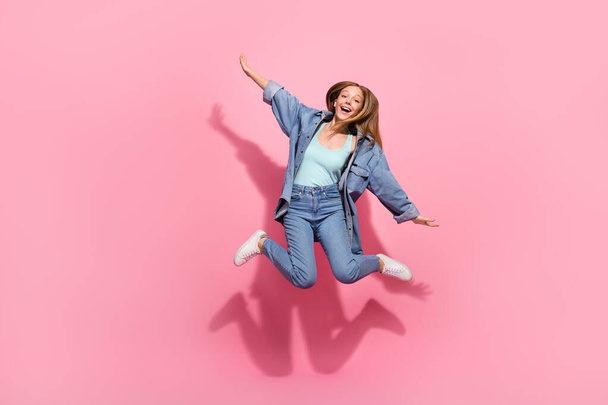 Full length photo of cheerful stylish girl wear denim clothes fly air hands wings enjoy summer holiday isolated on pink color background. - Foto, imagen
