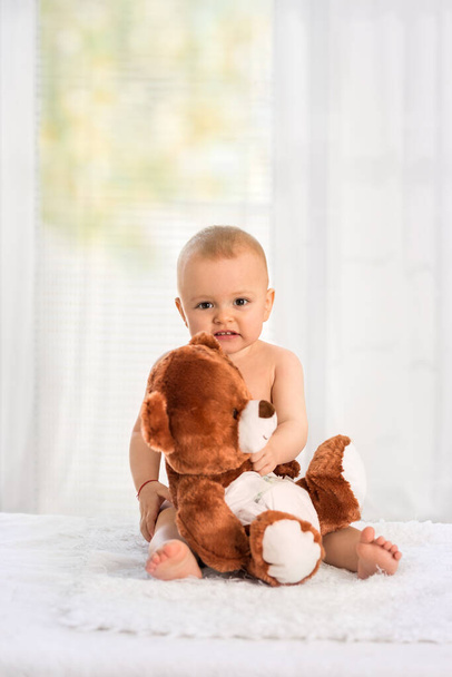 Nice baby holding his favorite toy on the table and is changing diapers - Фото, зображення