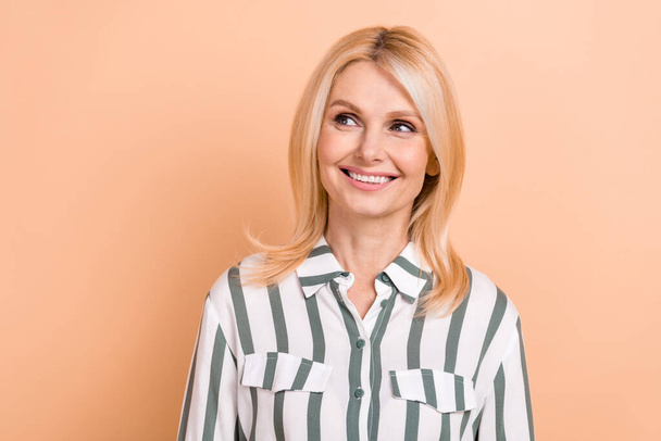 Portrait of optimistic satisfied woman with blond hairdo wear striped formalwear looking at empty space isolated on beige color background. - Valokuva, kuva