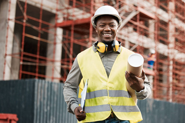 Architect, black man and plan outdoor at construction site building with a smile for development. Happy African engineer person portrait for project management, inspection or architecture blueprint. - Photo, Image
