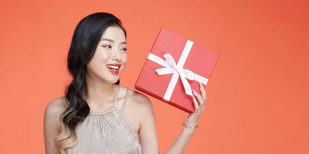 woman in evening dress holding opened present box isolated over red background - 写真・画像