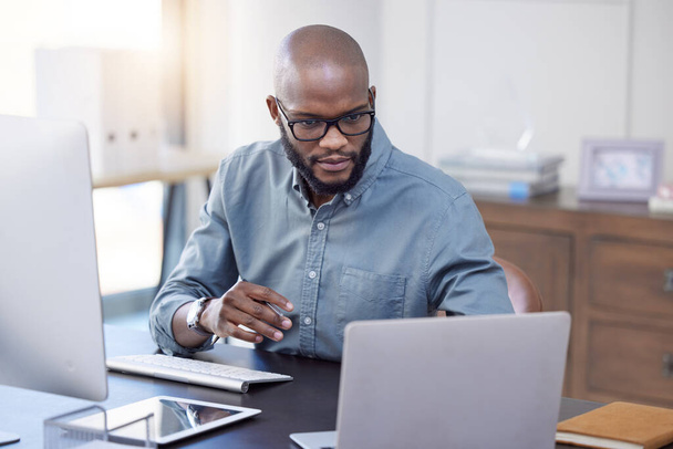 Programmer, laptop and black man reading software, coding or email in office. IT, computer and African professional working on cyber security, business or focus on research for information technology. - Photo, Image