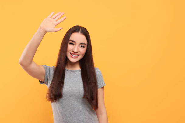 Happy woman giving high five on orange background, space for text - Fotoğraf, Görsel