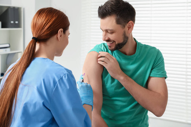 Doctor giving hepatitis vaccine to patient in clinic - Foto, imagen
