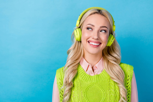 Portrait of gorgeous cheerful lady toothy smile listen music headphones look empty space isolated on blue color background. - Фото, изображение