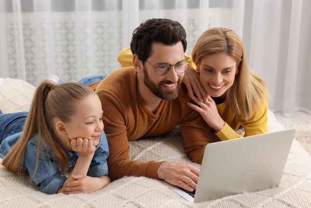 Happy family with laptop on bed at home - Foto, imagen