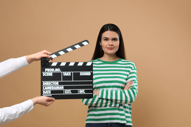 Actress performing while second assistant camera holding clapperboard on beige background. Film industry - Фото, изображение