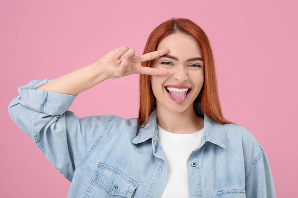 Happy woman showing her tongue on pink background - Foto, Imagem