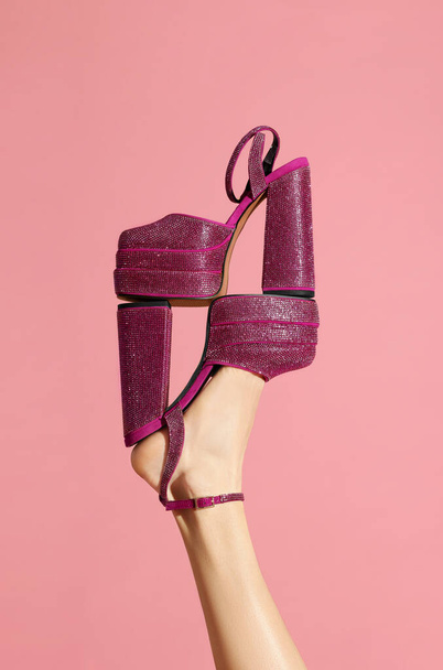 Woman wearing high heeled shoe with platform and square toes holding another one on pink background, closeup. Stylish presentation - Foto, immagini