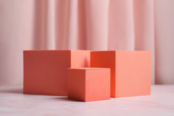 Orange cubes on pink marble table. Stylish presentation for product - Photo, Image