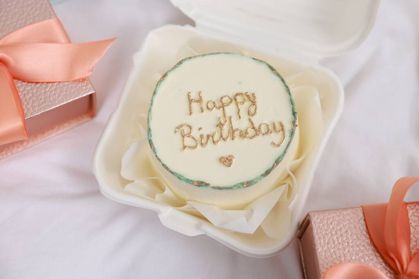 Delicious decorated cake and gifts on white cloth, flat lay. Happy Birthday - Fotografie, Obrázek