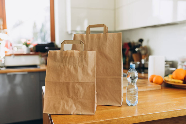 Food craft bags on the table on sunny day. Delivery in any weather around the clock to the client. Fast food eco packaging with big breakfast - 写真・画像