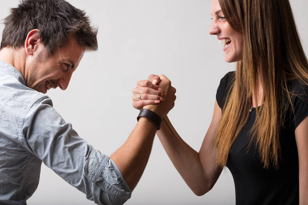 Mann und Frau, spielerisch trotzig, betreiben Armdrücken und verkörpern die Dichotomie von Freunden und Liebhabern, Rivalen und Konkurrenten, aber immer mit einem Sinn für Fairness und Spaß - Foto, Bild