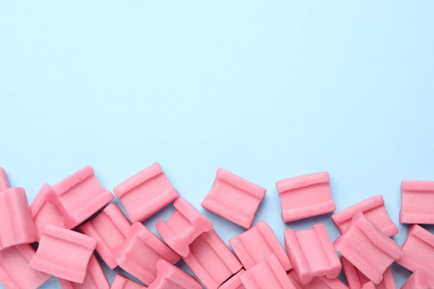 Tasty pink chewing gums on light blue background, flat lay. Space for text - Foto, afbeelding