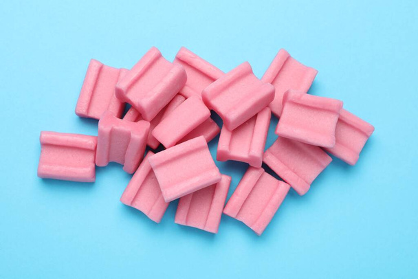 Tasty pink chewing gums on light blue background, flat lay - Fotoğraf, Görsel