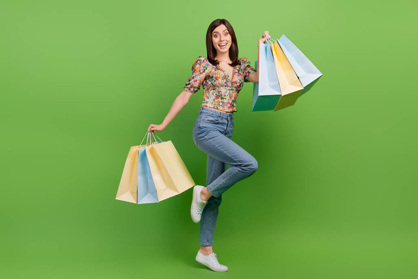 Full length portrait of cheerful lovely person hands hold boutique bags isolated on green color background. - Fotografie, Obrázek