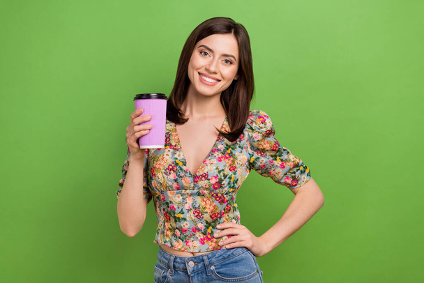 Portrait of stunning positive lady put hand waist hold coffee cup beaming smile isolated on green color background. - Foto, Imagem