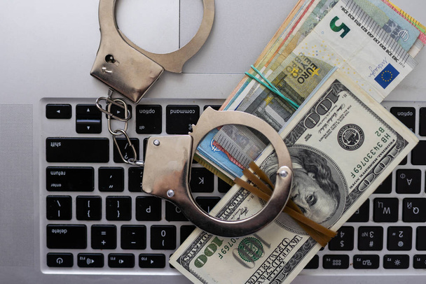 Police handcuffs lie on a lot of dollar bills. The concept of illegal possession of money, illegal transactions with US dollars. Economic Crime. High quality photo - Photo, Image