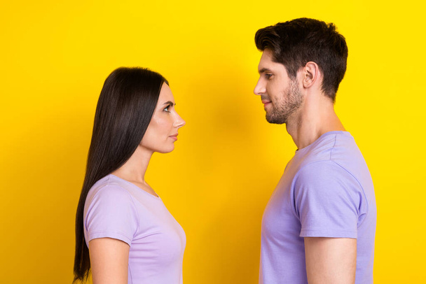 Profile portrait of two calm concentrated people look each other isolated on yellow color background. - Фото, зображення