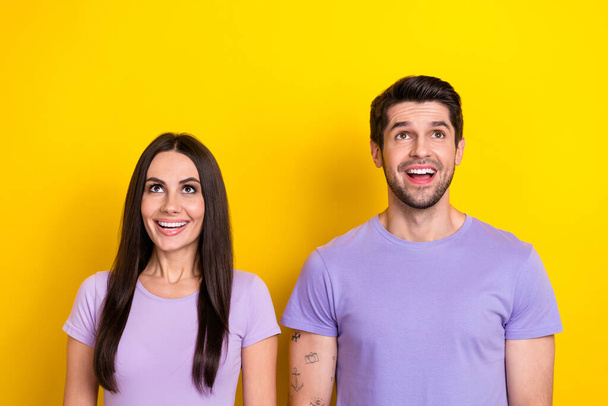 Portrait of astonished positive partners open mouth look up above empty space isolated on yellow color background. - Foto, afbeelding