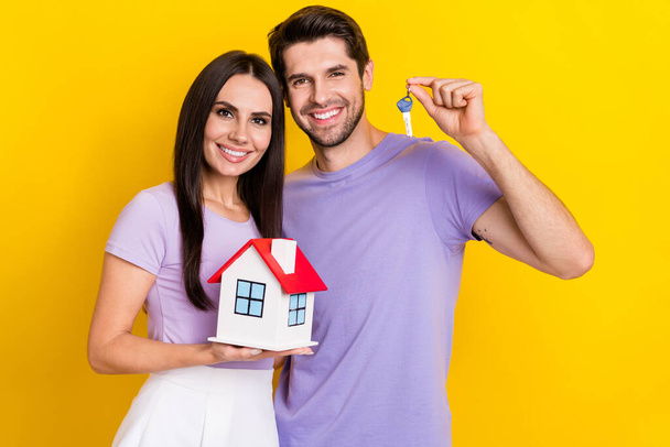 Photo portrait of pretty young girl male hold key small house buyer investing wear trendy purple outfit isolated on yellow color background. - Φωτογραφία, εικόνα