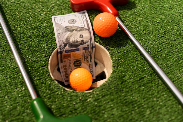 Money, mini golf balls on grass. Concept of sports bet. - Photo, Image