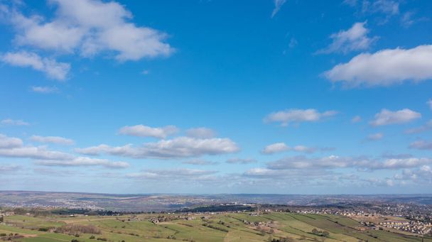 Aerial drone photo of the beautiful town of Thornton in Bradford in the UK showing the farmers fields in the Spring time on a hot sunny day with clouds in the sky. - 写真・画像