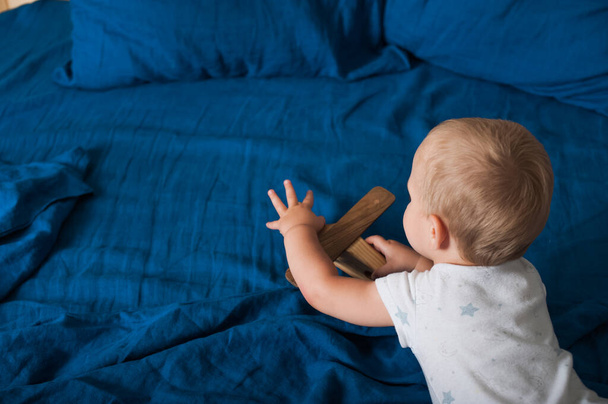 Малыш играет с самолетом на кровати крупным планом.. - Фото, изображение