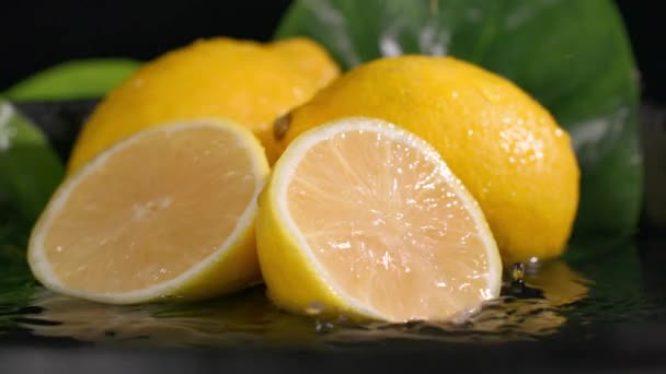 ломтик спелого здорового лимона падает на фрукты на темном фоне, крупным планом - Кадры, видео