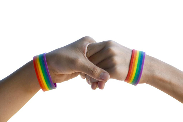 Μεμονωμένα χέρια ομοφυλόφιλων ζευγαριών που φορούν βραχιολάκι ουράνιο τόξο γύρω σε λευκό φόντο με μονοπάτια clippping. - Φωτογραφία, εικόνα