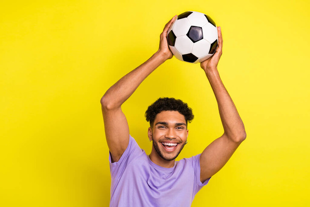 Foto de un chico joven atrapar pelota jugando fútbol divertirse deportista positivo despreocupado actividad física aislada en el fondo de color amarillo. - Foto, imagen
