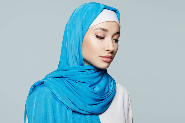 Όμορφη νεαρή μουσουλμάνα. Όμορφο κορίτσι με μαντίλα. μόδα ανατολίτικο μοντέλο στυλ. Ασιάτισσα κυρία πάνω από μπλε φόντο - Φωτογραφία, εικόνα