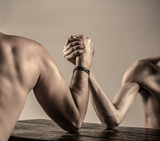 Two mans hands clasped arm wrestling, strong and weak, unequal match. Arm wrestling.Arms wrestling thin hand, big strong arm in studio. - Fotó, kép