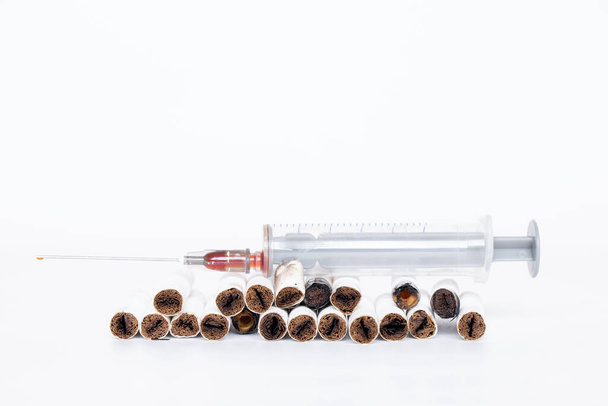 Spritze und Zigaretten liegen auf weißem Hintergrund in Großaufnahme, Sucht und schlechte Angewohnheit - Foto, Bild