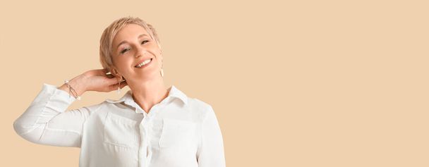 Smiling mature woman on beige background with space for text - Foto, imagen