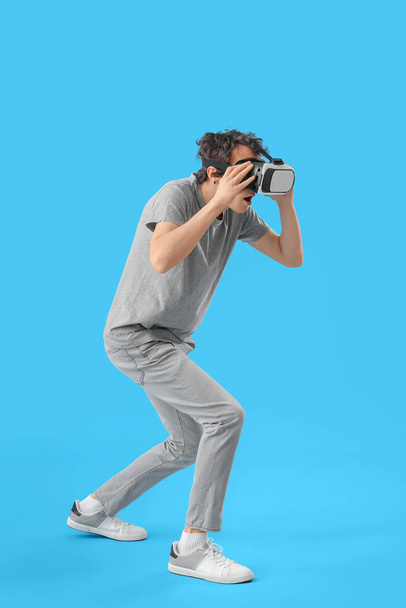 Young man using VR glasses on blue background - Fotoğraf, Görsel