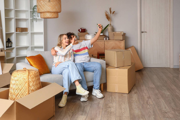 Young couple taking selfie in room on moving day - Photo, Image
