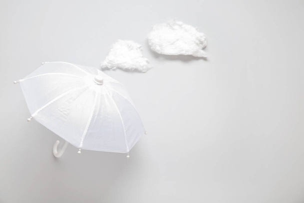 Kompozycja z parasolem i chmurami na białym tle - Zdjęcie, obraz