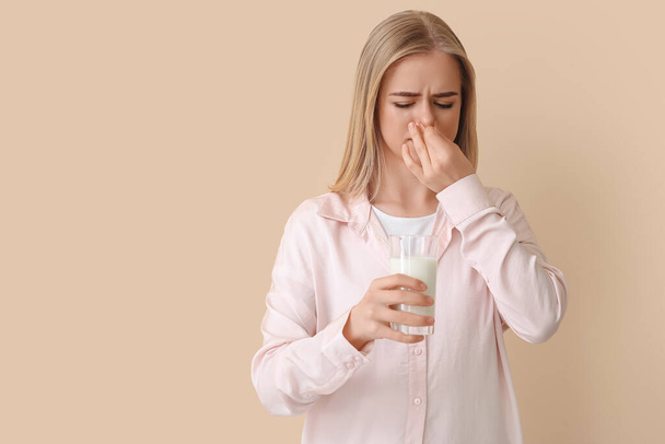 Young woman with lactose intolerance on beige background - Foto, afbeelding