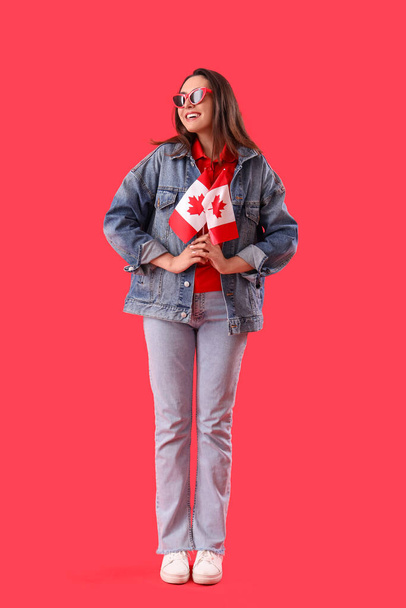 Νεαρή γυναίκα με σημαίες του Καναδά σε κόκκινο φόντο - Φωτογραφία, εικόνα