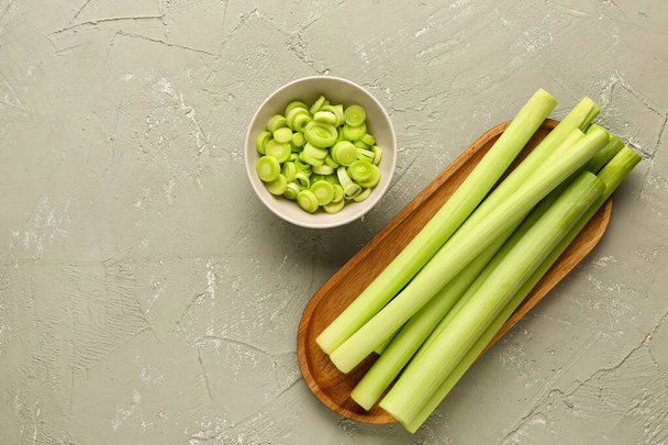 Board and bowl with slices of fresh leek on grey background - Photo, Image