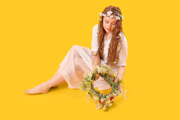 Beautiful young woman with flower wreath on yellow background. Summer solstice - Fotografie, Obrázek
