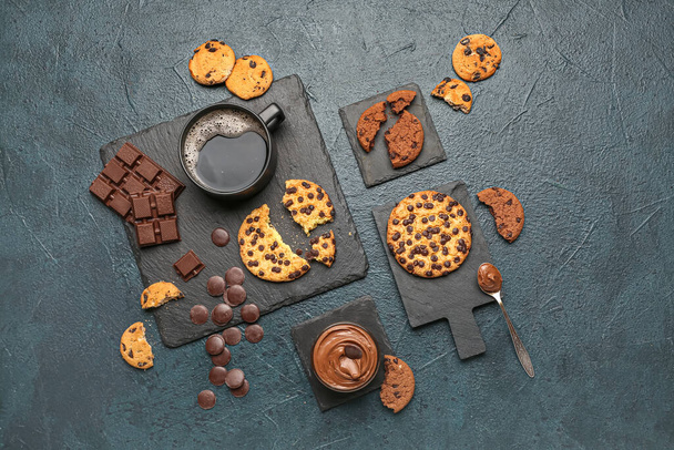 Kopje koffie met koekjes, chocolade en planken op donkere tafel - Foto, afbeelding