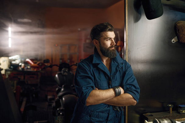 Pensive repairman thinking and searching idea while looking at window of motorcycle workshop. Solving complex repair problems concept - Photo, Image