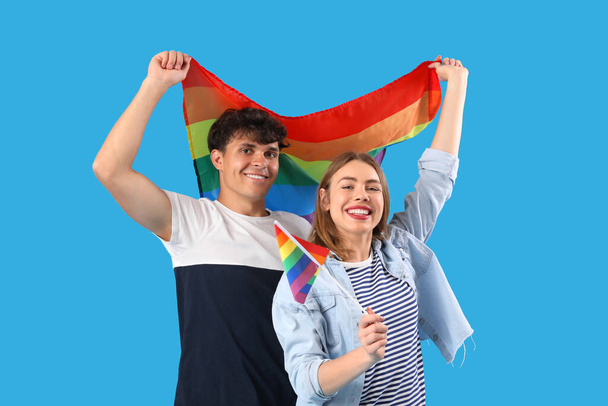 Glückliches junges Paar mit LGBT-Flaggen auf blauem Hintergrund - Foto, Bild