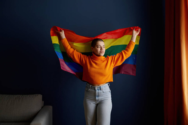 Portrait of young lesbian woman holding lgbtq pride flag performing for sexual identity, freedom and equality - Photo, Image