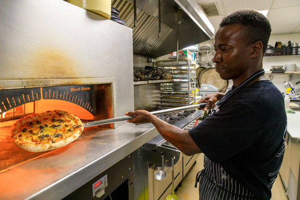 Oliver, British Columbia, Canada - May 15, 2023: Chef removing cooked pizza from wood burning oven at Miradoro restaurant at Tinhorn Creek Winery in Oliver, BC, Canada. - 写真・画像
