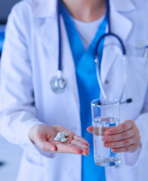 shot of doctors hands holding pills and glass of water at clinic - Fotografie, Obrázek