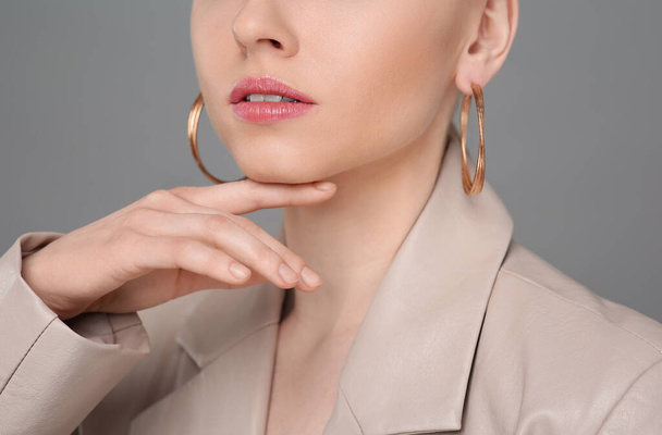 Woman with elegant earrings on gray background, closeup - Photo, image