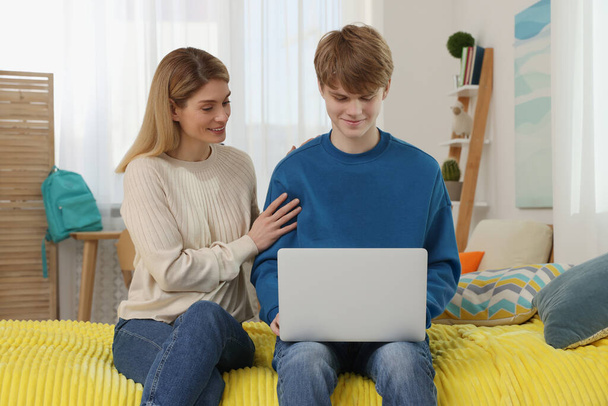 Happy mother and her teenage son with laptop at home - 写真・画像